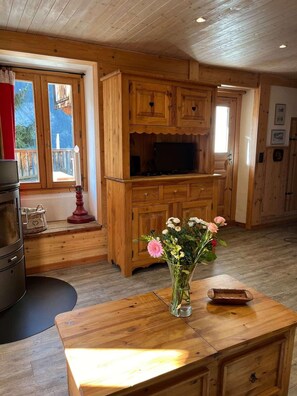 A wooden interior with a TV on a cabinet, a vase with flowers on a table, and a window with curtains. - Fireplace or stove, parking, tv, 40m², Peisey-Vallandry (Peisey-Nancroix)