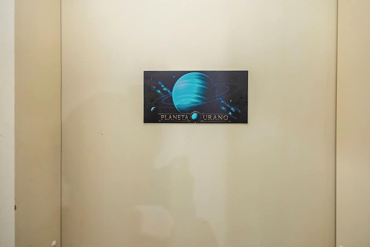 Una pared con un letrero que dice 'PLANETA URANO' y que muestra una representación de un planeta con anillos.