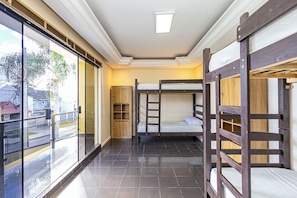 A room with bunk beds, a sliding glass door, and a ceiling light.