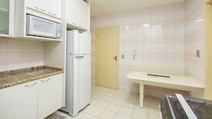 A kitchen with white cabinets, a microwave, a refrigerator, a sink, and a tiled backsplash.