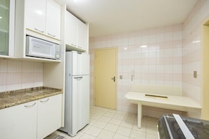 A kitchen with white cabinets, a microwave, a refrigerator, a sink, and a tiled backsplash.