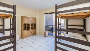 A room with bunk beds, a wooden wardrobe, and a view through a glass door.