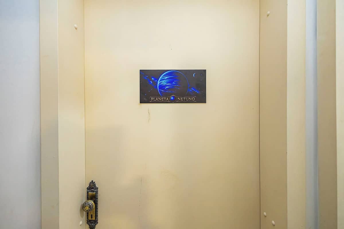 Una puerta con un letrero que dice 'PLANETA NETUNO' y una mirilla a la izquierda.