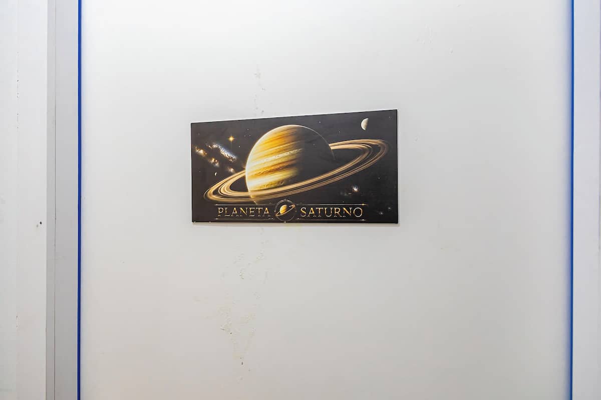 Una pared con un cartel de temática espacial que muestra un planeta y anillos, y el texto 'PLANETA SATURNO'.