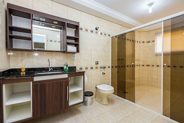 A bathroom with a shower, toilet, vanity with shelves, and a mirror.