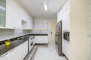 A kitchen with white cabinets, a refrigerator, a microwave, and a stove.