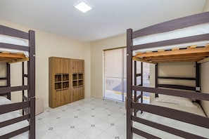 A room with bunk beds, a wooden wardrobe, and a tiled floor.