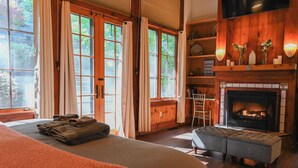 Une pièce confortable avec un lit, une cheminée et de grandes fenêtres avec des rideaux.