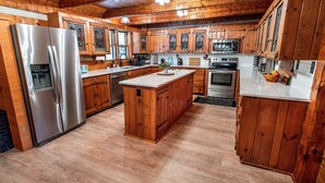 Eine Küche mit Holzausstattung, einem Edelstahlkühlschrank, einer Mikrowelle und einem Backofen.