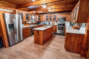 A kitchen with wooden cabinets, a stainless steel refrigerator, a microwave, and an oven. - Log Cabin, Theater, Arcade & Sauna | Beaver Cabin (Weaverville)