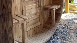 Un sauna en bois avec une porte, un petit banc et un mur en pierre.