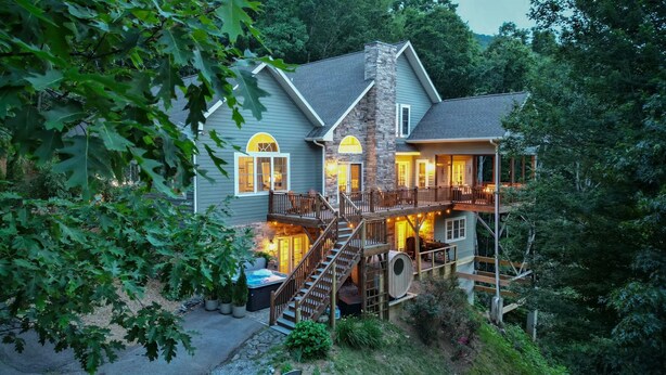 Une maison à deux étages avec une façade en pierre, une terrasse en bois et un escalier menant à l’étage supérieur.
