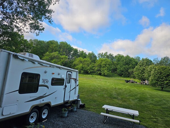 A recreational vehicle (RV) parked in a grassy area with a picnic table nearby.