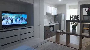 Una cocina moderna con armarios blancos, horno empotrado y refrigerador.