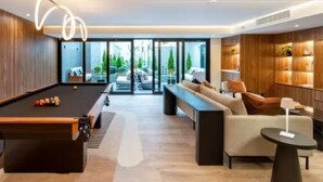 Una sala de estar moderna con mesa de billar, sofá, mesa de centro y chimenea.