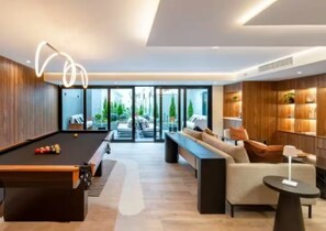 A modern living room with a pool table, a sofa, a coffee table, and a fireplace. - Cozy 1-bedroom studio in gorgeous Miraflores with AC (Miraflores)