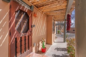 Ein Gebäudeeingang mit Holztür, einem Blumentopf und einer roten Chili-Dekoration.