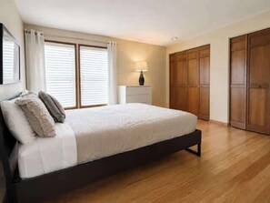 A bedroom with a bed, a nightstand, a lamp, and a wardrobe. - Modern 3BR Home Near UO, Autzen Stadium, Oakway Center & Hayward Field (Eugene)