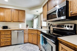 A kitchen with wooden cabinets, stainless steel appliances, and a dishwasher. - Modern 3BR Home Near UO, Autzen Stadium, Oakway Center & Hayward Field (Eugene)