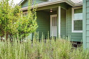 A green house with a white door and window, surrounded by tall grass. - Modern 3BR Home Near UO, Autzen Stadium, Oakway Center & Hayward Field (Eugene)