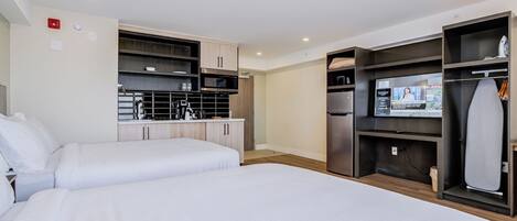 Habitación de hotel con dos camas, kitchenette, televisor de pantalla plana y armario.
