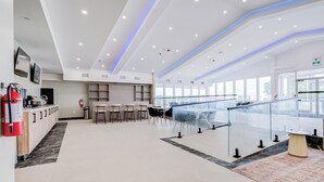Eine moderne Hotelhalle mit einer Rezeption, einer Sitzecke und großen Fenstern.