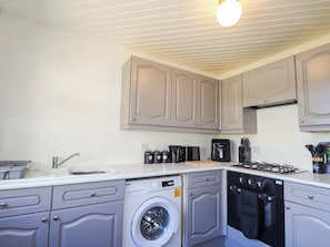 A compact kitchen with a washing machine, dishwasher, and a coffee maker.