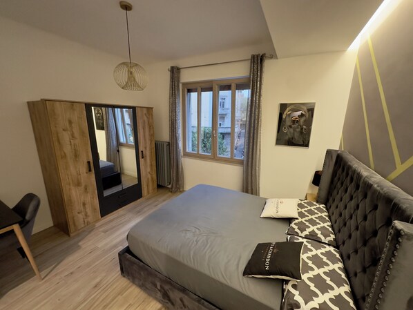 Une chambre à coucher comprenant un lit, une armoire, une chaise, une fenêtre et un luminaire suspendu.