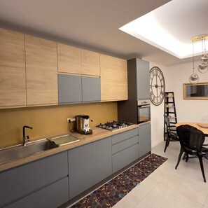 Une cuisine moderne avec des meubles gris, une cuisinière à gaz et une machine à café.