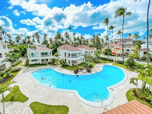 A resort with a large swimming pool, multiple-story buildings, and palm trees. - Caribbean Los Corales Villas Suite SPA (Punta Cana)