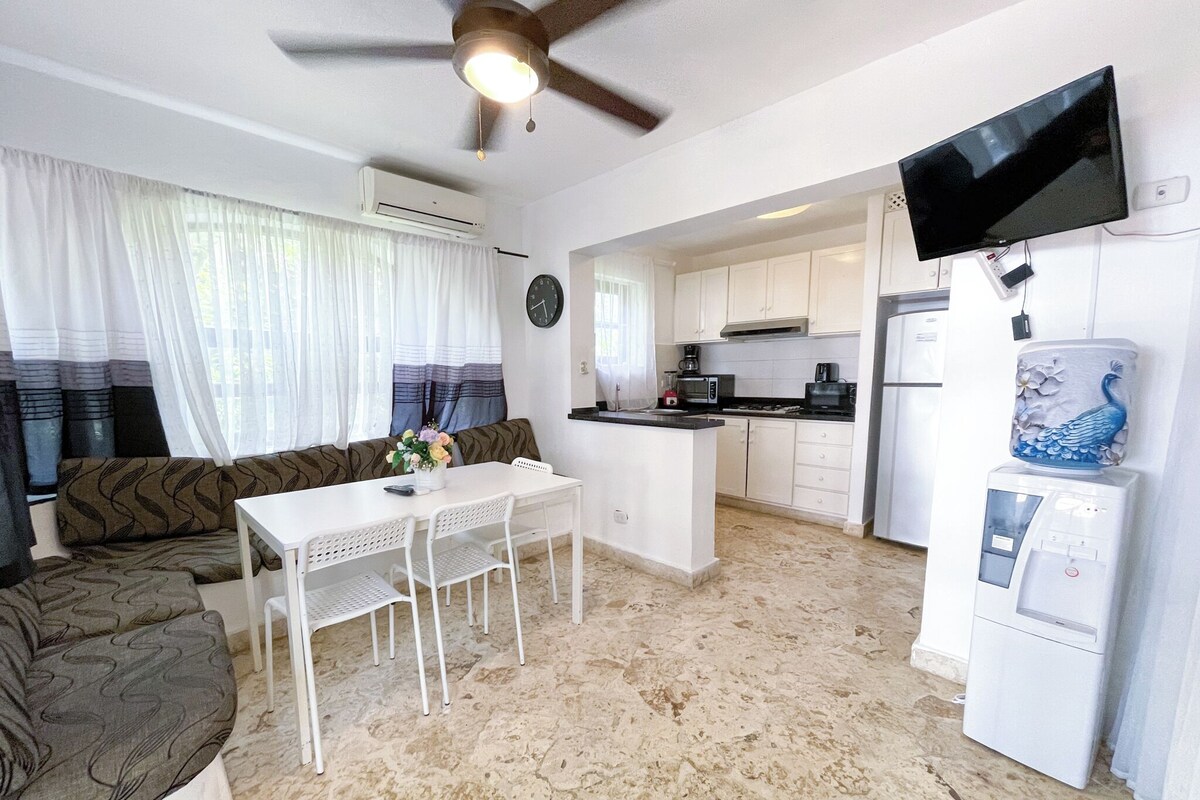 A compact living space with a kitchenette, a dining area, and a sofa.