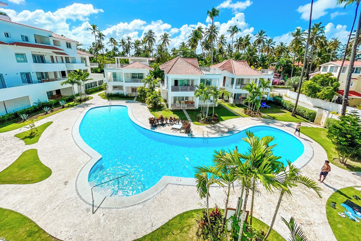Un resort con una grande piscina, diversi edifici e palme.
