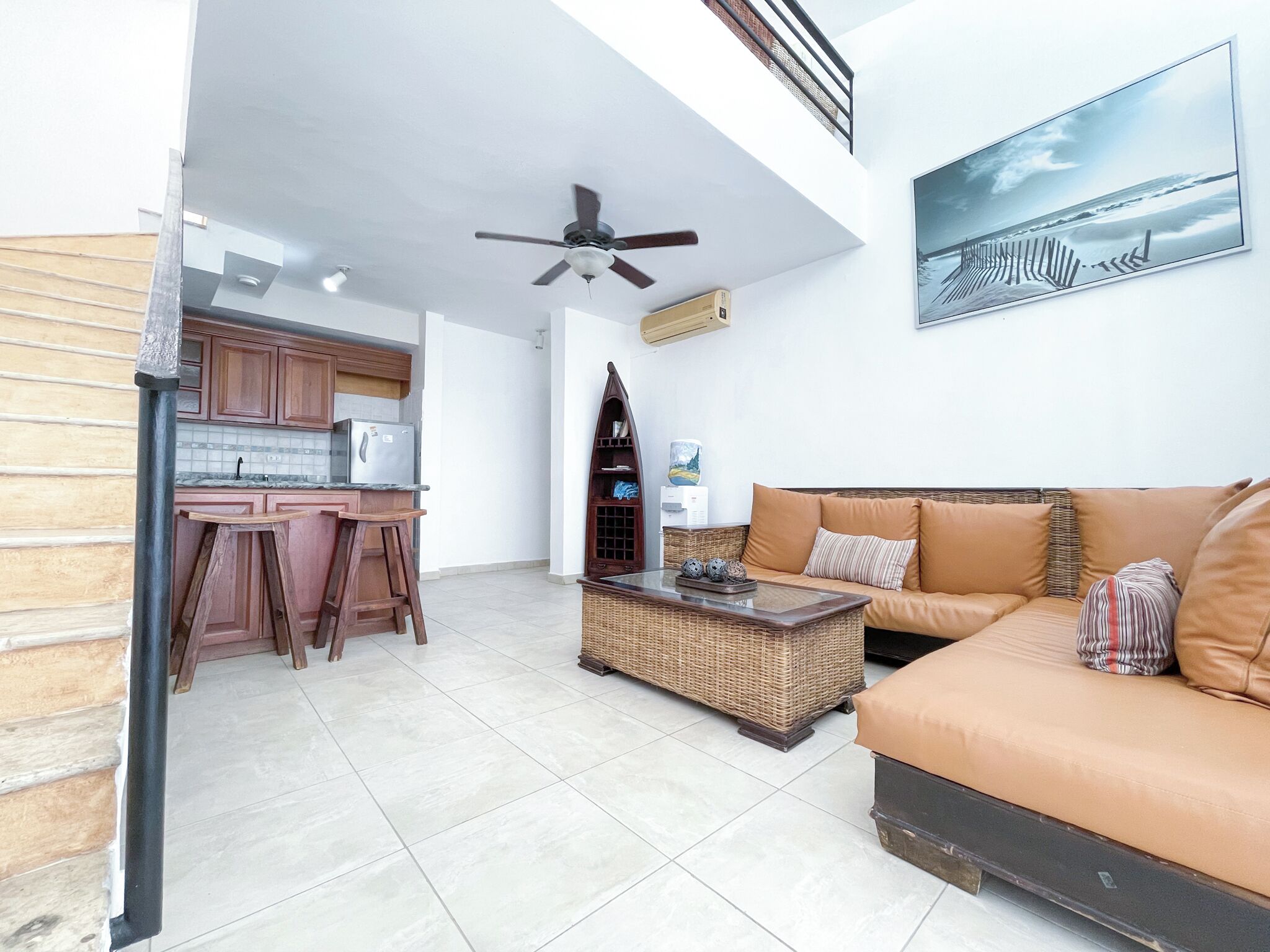 Un espacio moderno multifuncional con cocina, comedor, sofá y ventilador de techo.