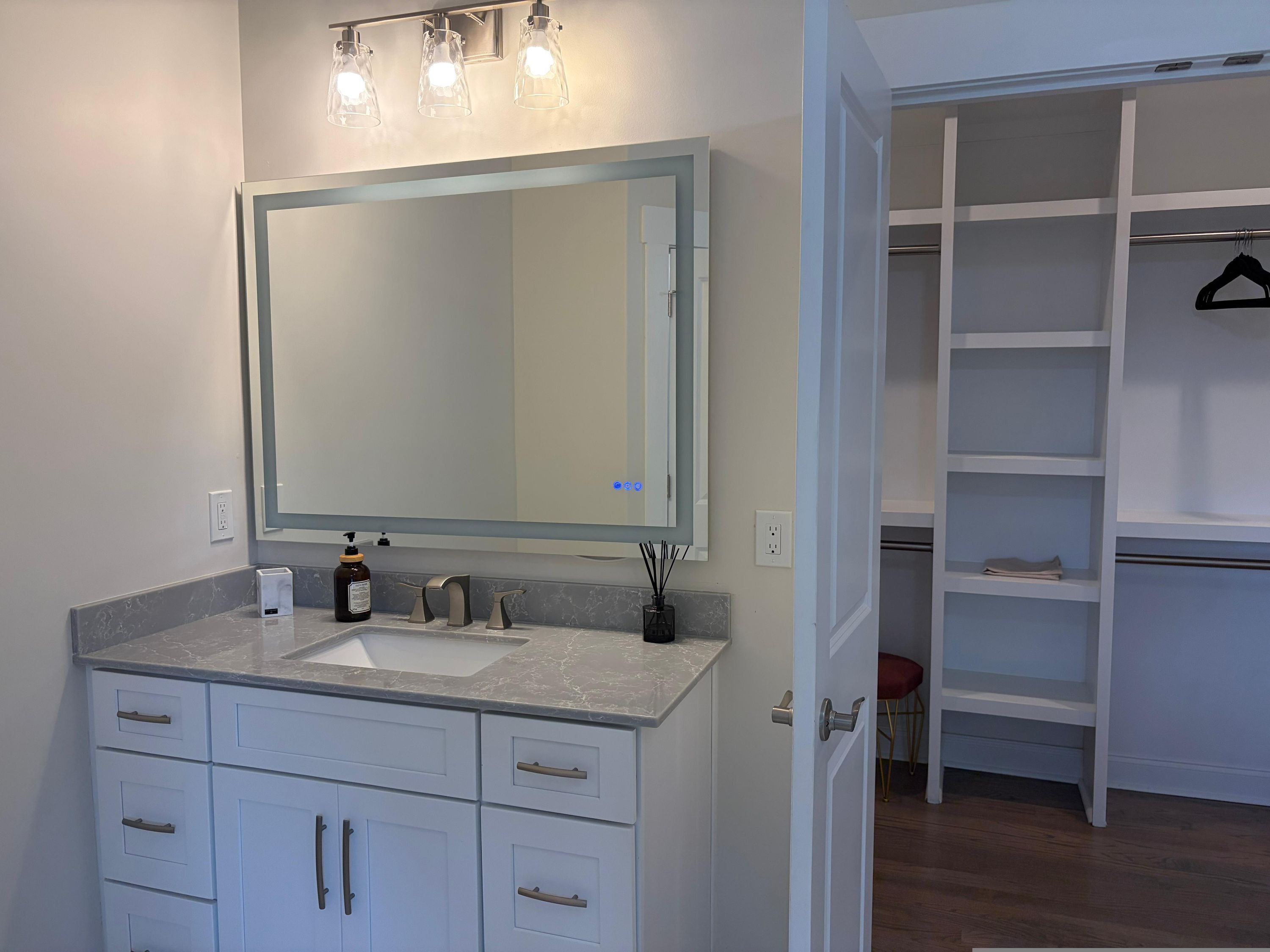 A bathroom with a large mirror, a sink, and a cabinet with drawers.