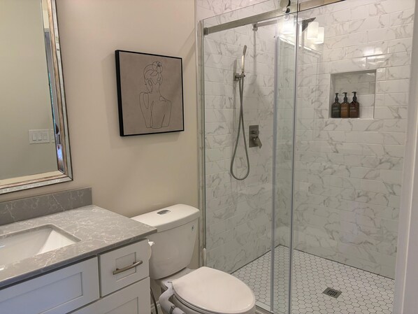 Ein modernes Badezimmer mit Marmorwaschbecken, Toilette und Duschkabine.