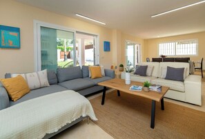 A living room with a sofa, a coffee table, and a dining area with a table and chairs.