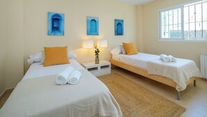 A hotel room with two single beds, a small table with a lamp, and a window with a view. - Villa Morret Moraira by Cabrera Homes (Teulada)