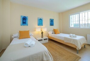 Ein Hotelzimmer mit zwei Einzelbetten, einem kleinen Tisch mit einer Lampe und einem Fenster mit Blick.