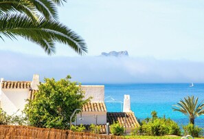 A coastal view with a clear sky, a distant mountain, and a sailboat on the water.