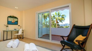 A room with a bed, a chair, a desk, a painting, and a sliding glass door to a balcony. - Villa Morret Moraira by Cabrera Homes (Teulada)