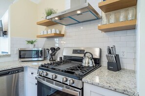 Una cocina moderna con estufa, microondas y lavavajillas de acero inoxidable.