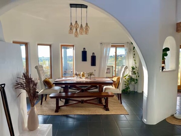 A dining area with a large table, chairs, and a hanging light fixture. - Casa Encantado in Eldorado (Santa Fe)