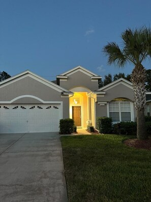 A residential house with a garage, a front entrance, and a palm tree.