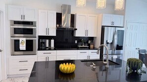 A modern kitchen with white cabinets, stainless steel appliances, and a central island with a decorative yellow object.