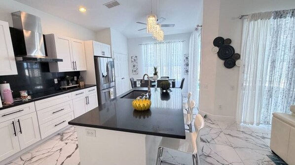 A modern kitchen with white cabinets, a black countertop, and a central island.