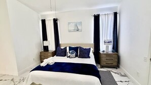 Une chambre d’hôtel bien rangée, avec un lit, deux tables de chevet, une lampe et un tableau au mur.