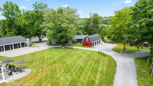 A residential property with a well-maintained lawn, a red barn, and a covered patio area. - Romantic Barn Loft | Wine Country & Weddings (Paeonian Springs)