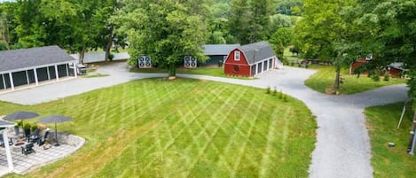 Il s’agit d’une propriété résidentielle dotée d’une pelouse bien entretenue, d’une grange rouge et d’un patio couvert.