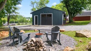 A rustic outdoor seating area with Adirondack chairs, a fire pit, and a wooden table. - Romantic Barn Loft | Wine Country & Weddings (Paeonian Springs)