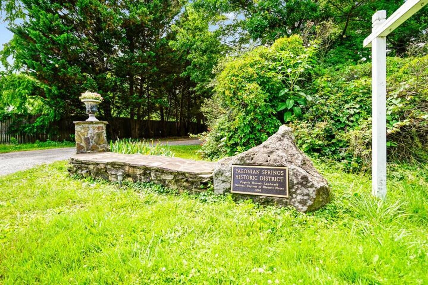 Un chemin de pierre mène à un panneau indiquant le site historique de Paeonian Springs.